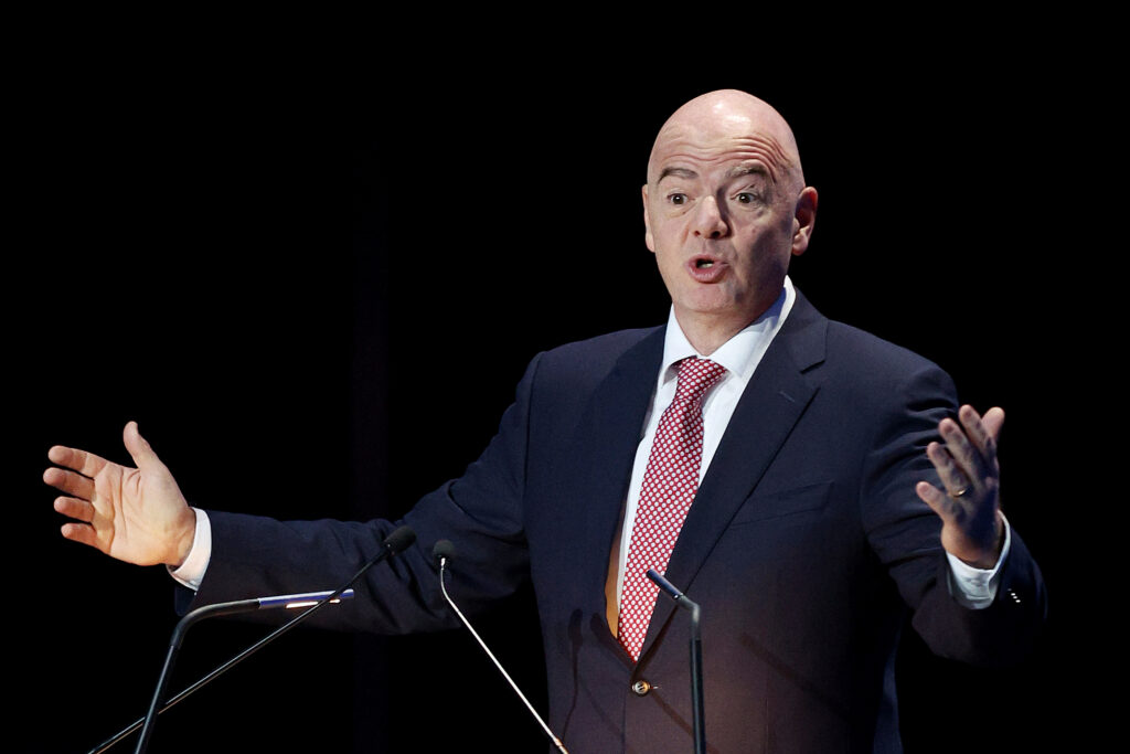 Gianni Infantino mit Anzug und Krawatte steht vor Rednerpult und spricht über ein Mikrofon