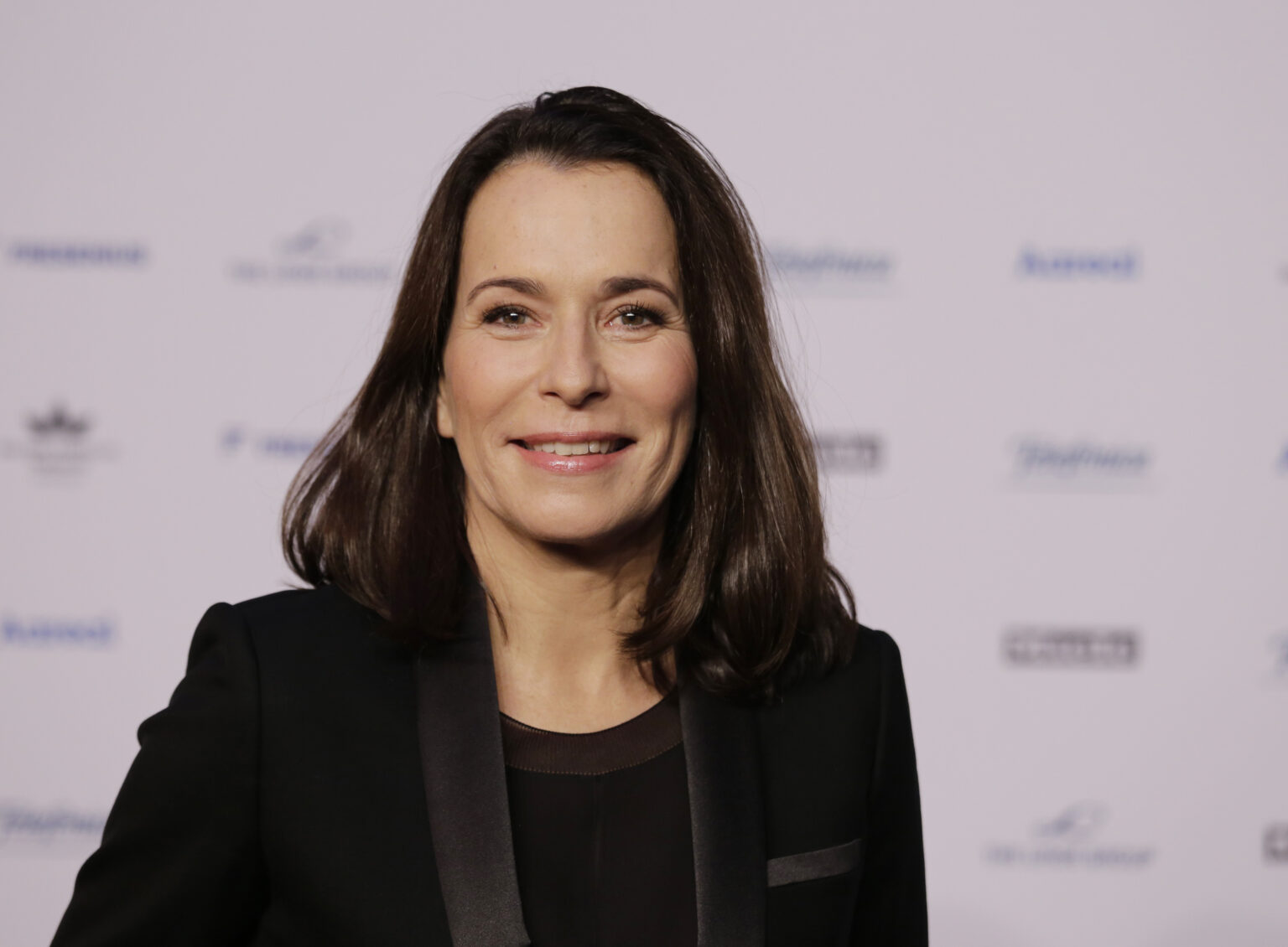 Anne Will posiert vor Werbewand