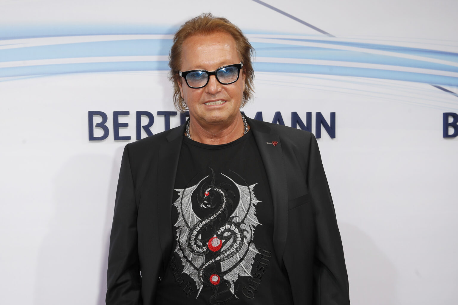 Robert Geiss mit Brille posiert vor Werbewand