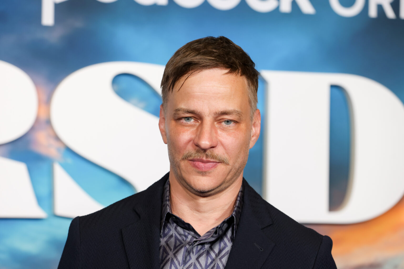 Tom Wlaschiha posiert vor Werbetafel