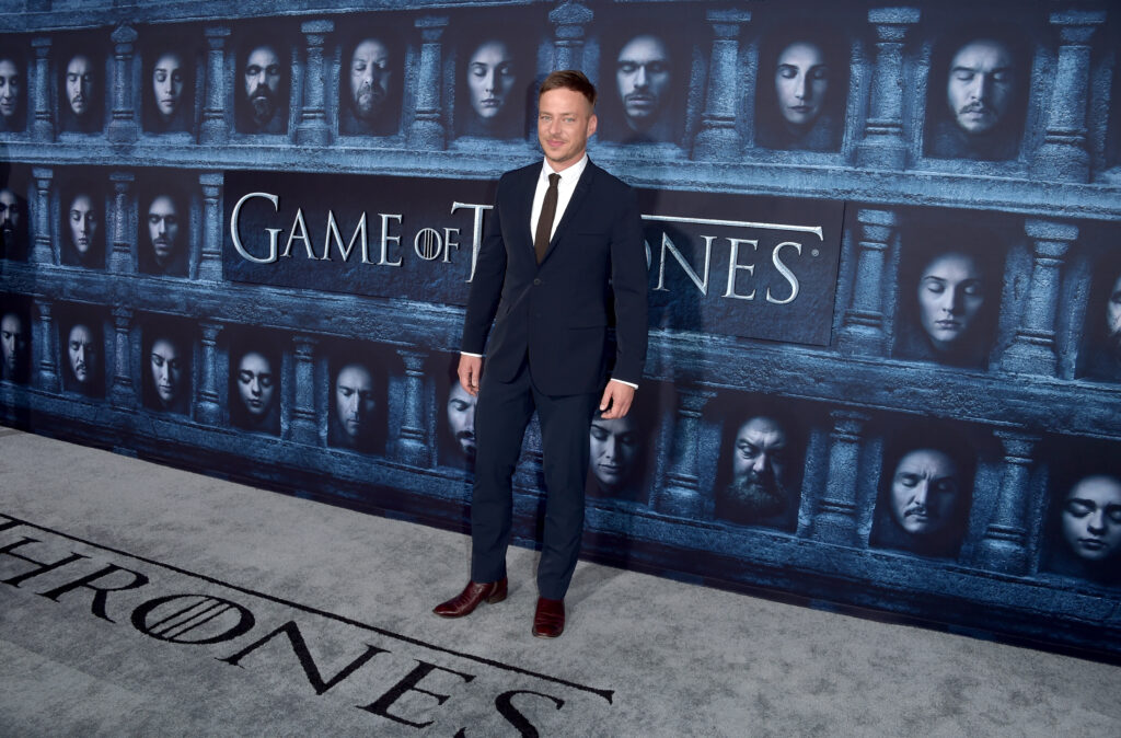 Tom Wlaschiha posiert vor Werbetafel