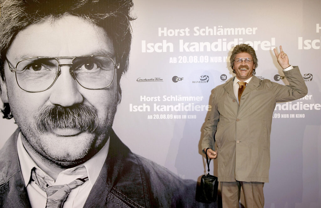 Hape Kerling steht vor dem Poster als Horst Schlämmer verkleidet