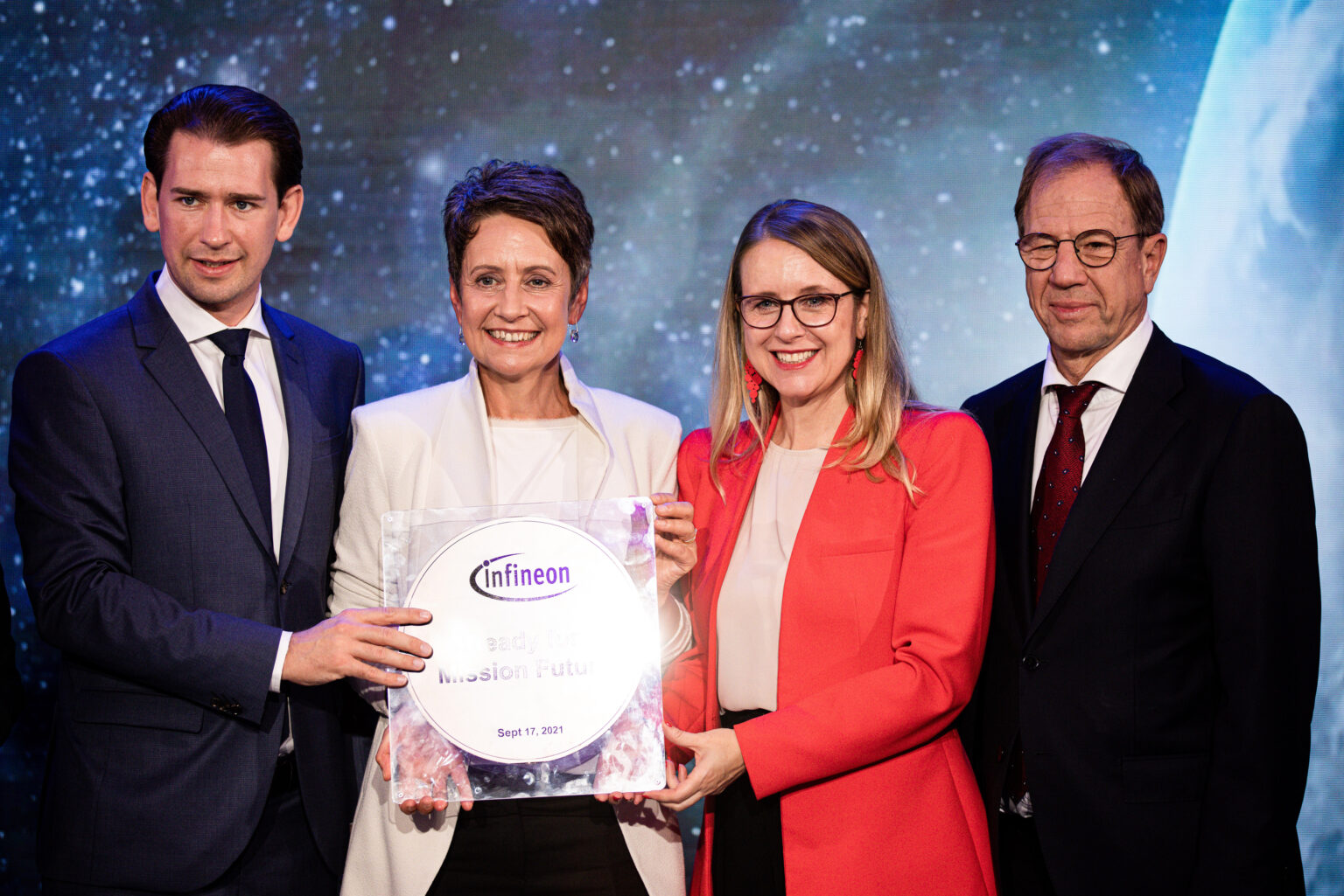 Sabine Herlischka hält das Firmenschild von infineon in Händen. sie steht neben Sebastian Kurz und zwei weiteren Personen