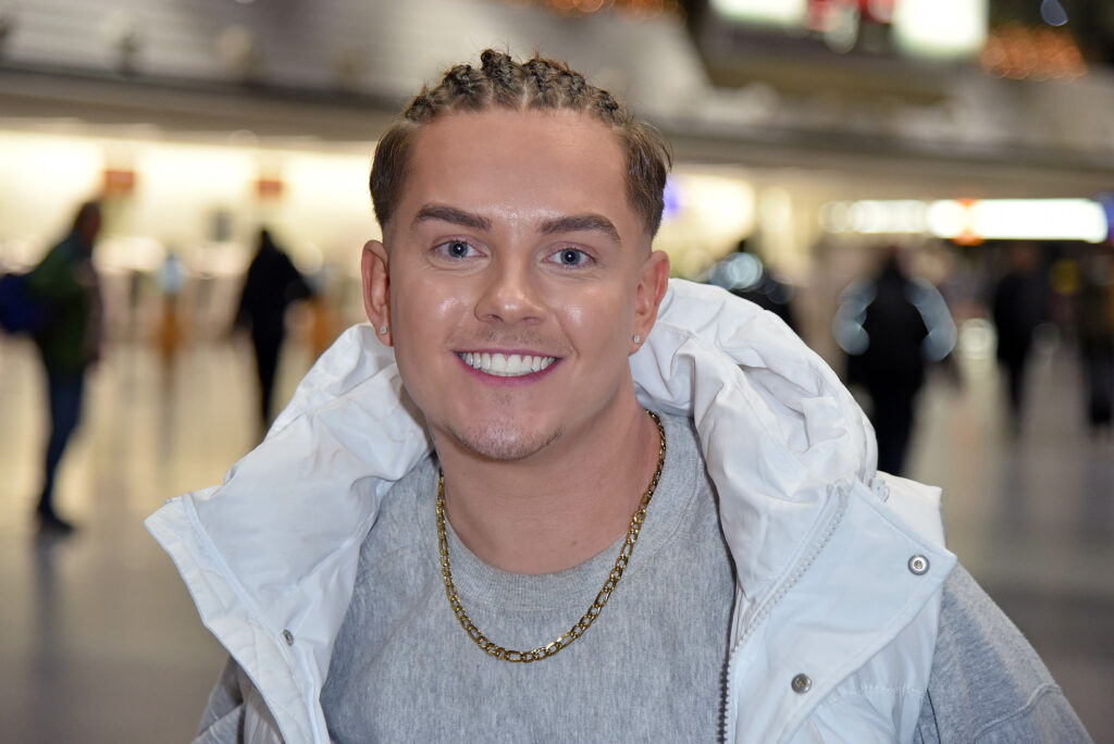Tim Maximilian Kampmann alias twenty4tim trägt eine weiße Jacke und blickt lächelnd in die Kamera