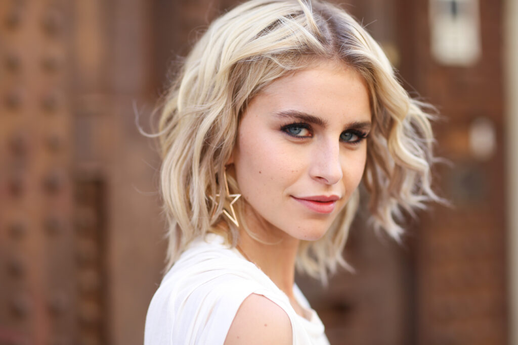 Caro Daur mit blonden Haaren und weißem Oberteil lächelt in die Kamera