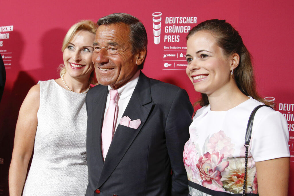Wolfgang Grupp Wolfgang Grupp steht mit seiner Ehefrau und Tochter Bonita vor einem roten Plakat mit der Aufschrift: Deutscher Gründer Preis