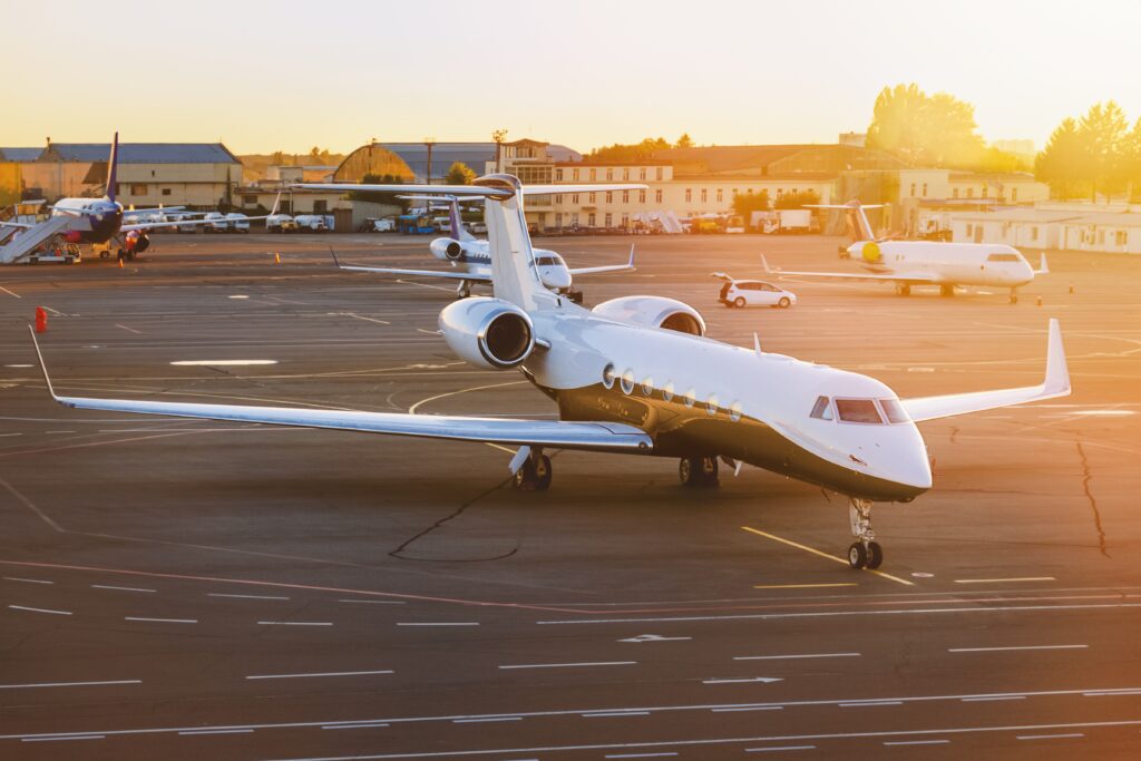 Andreas Bierwirth kleines Privatflugzeug bei Sonnenuntergang auf einem Flugplatz. Dahinter drei weitere kleine Maschinen und ein Auto