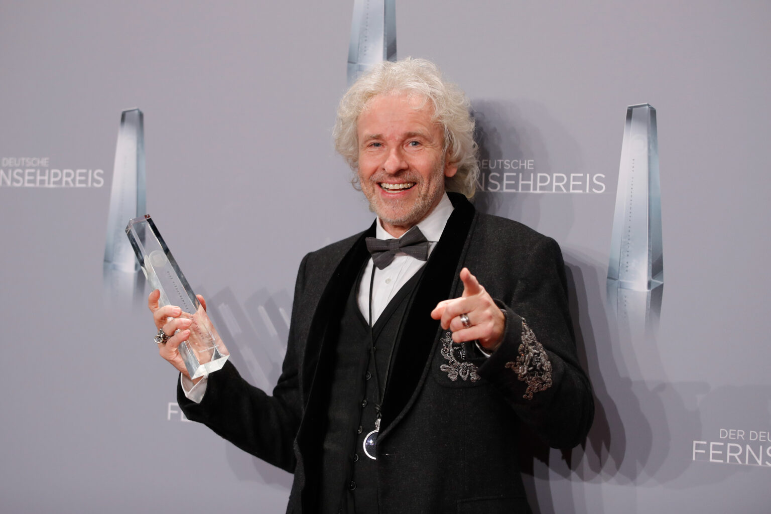 Thomas Gottschalk mit schwarzem Smoking und einer gläsernen Trophäe in der Hand