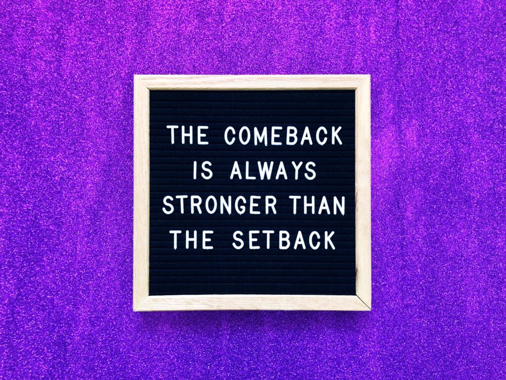Simone Menner violetter Hintergrund dafür ein Schild mit der Aufschrift The comeback is always stronger than the setback