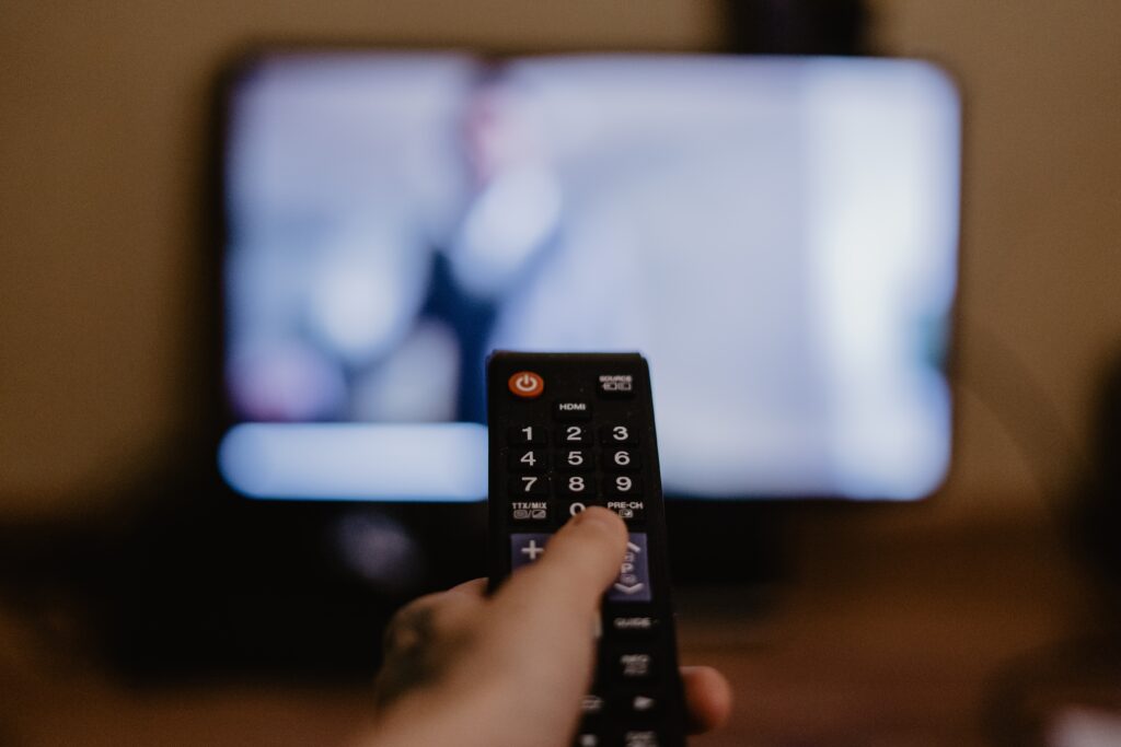 Fernbedienung die auf einen Fernseher gerichtet ist, der nur unscharf zu erkennen ist