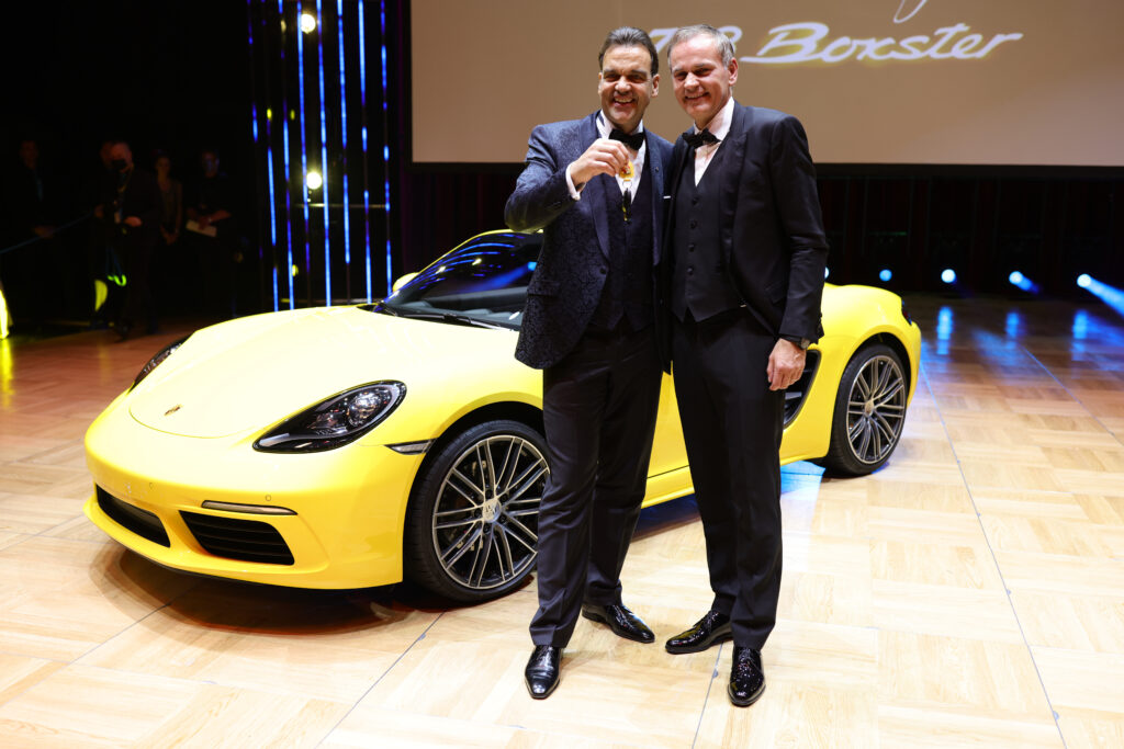 Christoph Gröner posiert mit Oliver Blume vor einem gelben Porsche