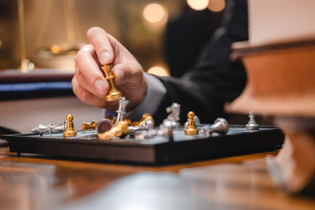 Martin Winterkorn Schachbrett mit goldenen und silbernen Figuren. Eine Hand hält den goldenen König. Die restlichen Figuren liegen am Schachbrett
