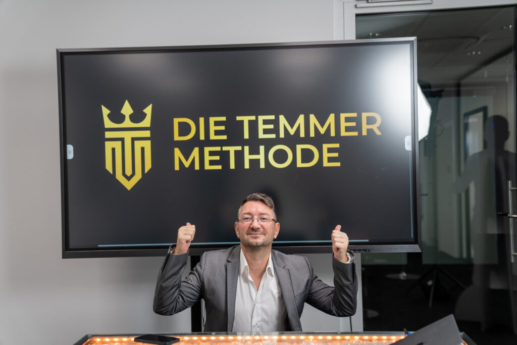 Walter Temmer zeigt auf Fernseher,auf dem 