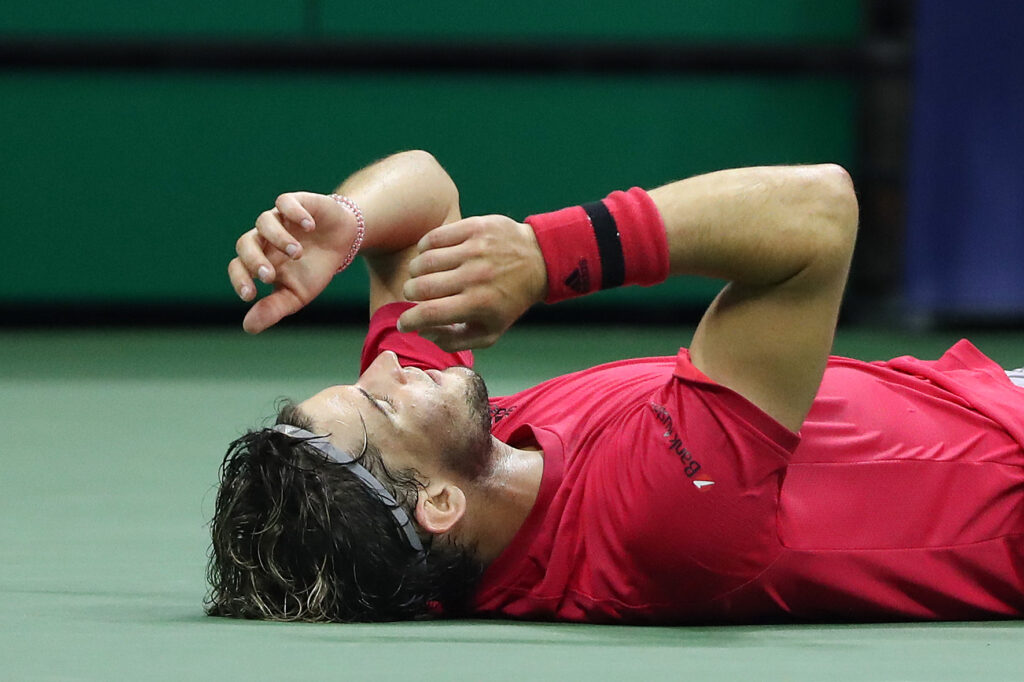 Dominic Thiem mit rotem T-Shirt liegt am Boden