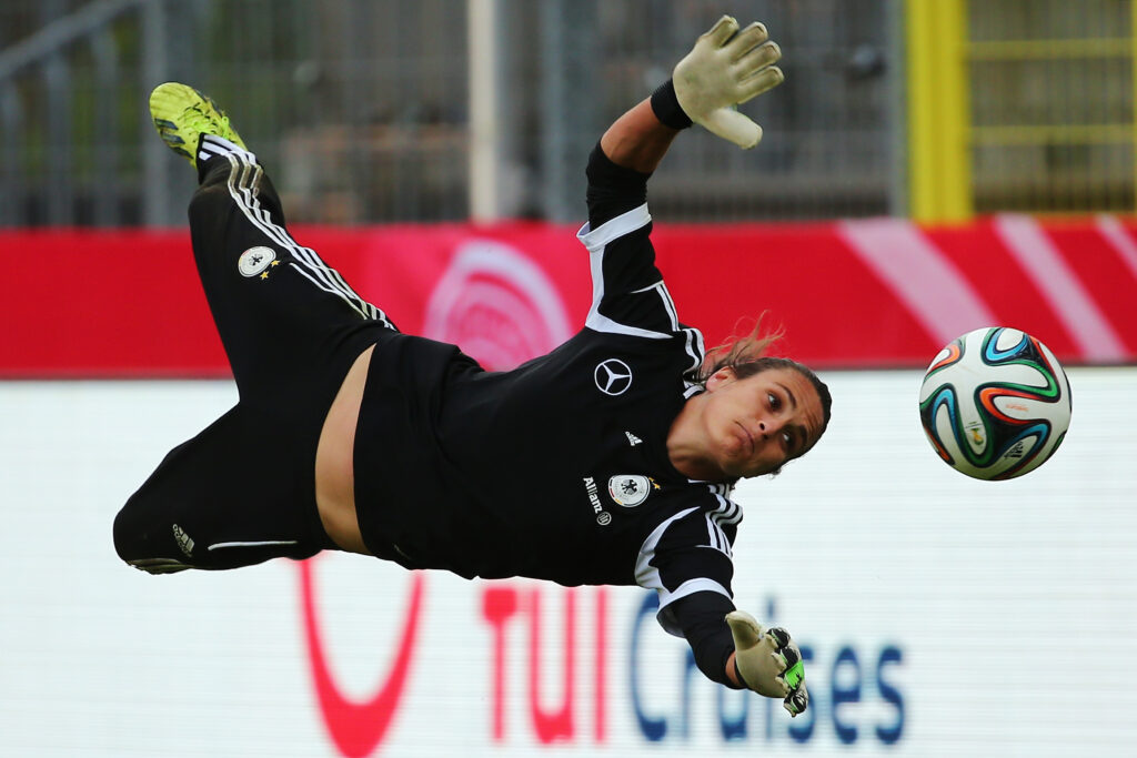Nadine Angerer springt seitlich zu einem Fußball