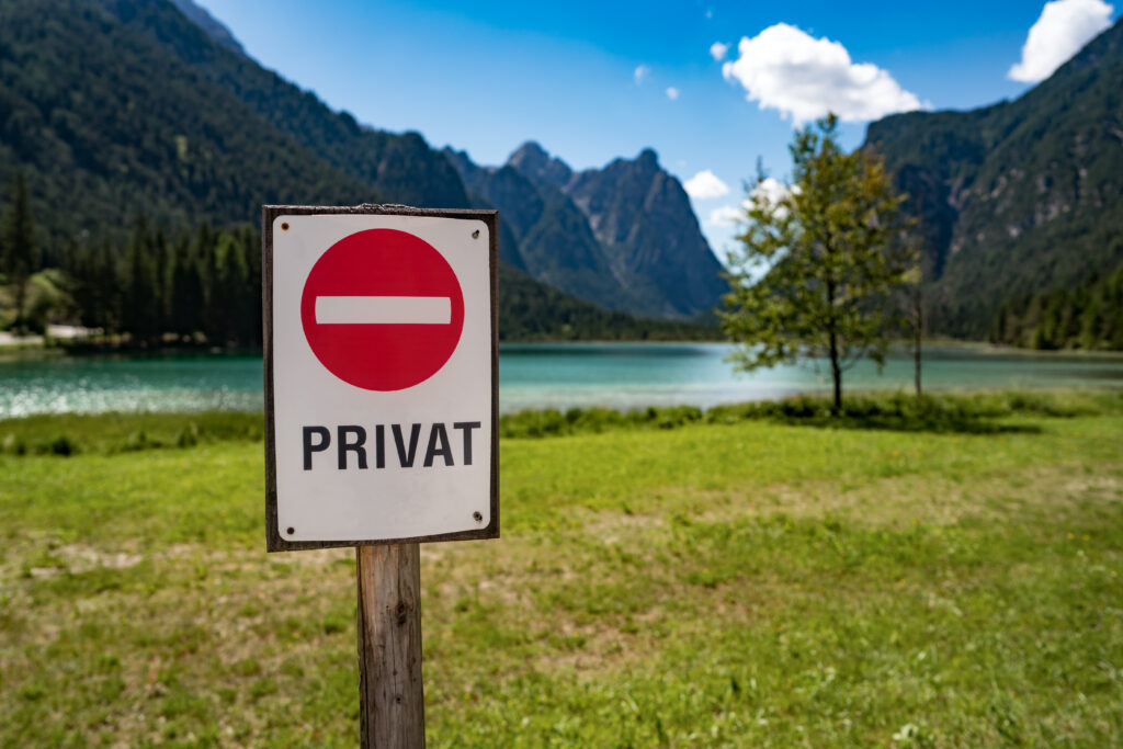 Schild mit Privat an einem See mit einer Bergkulisse