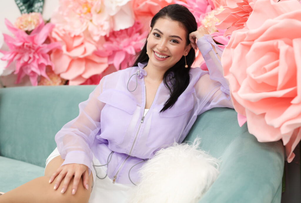 Paola Maria sitzt auf einem Sofa mit vielen rosa Blumen herum