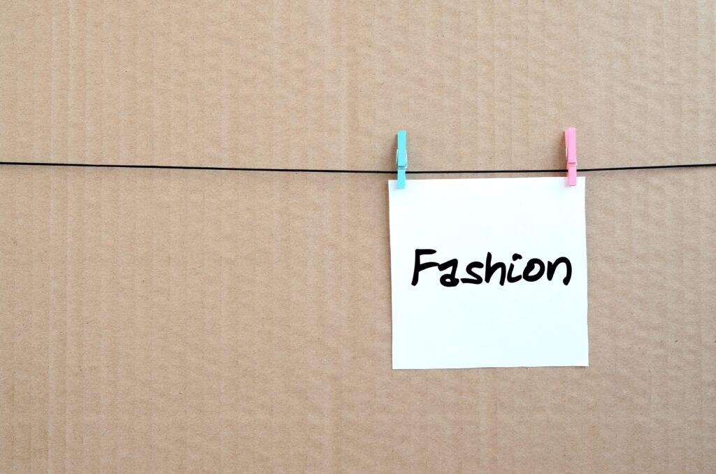 Das Wort Fashion auf einer Karte die mit zwei Kluppen auf einer Leine hängt