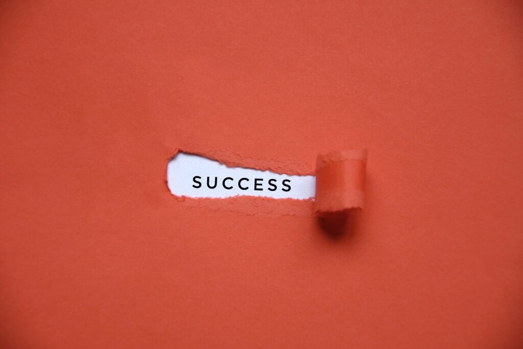 roter Hintergrund und SUCCESS geschrieben dahinter - das rote Papier ist über sucess aufgerissen