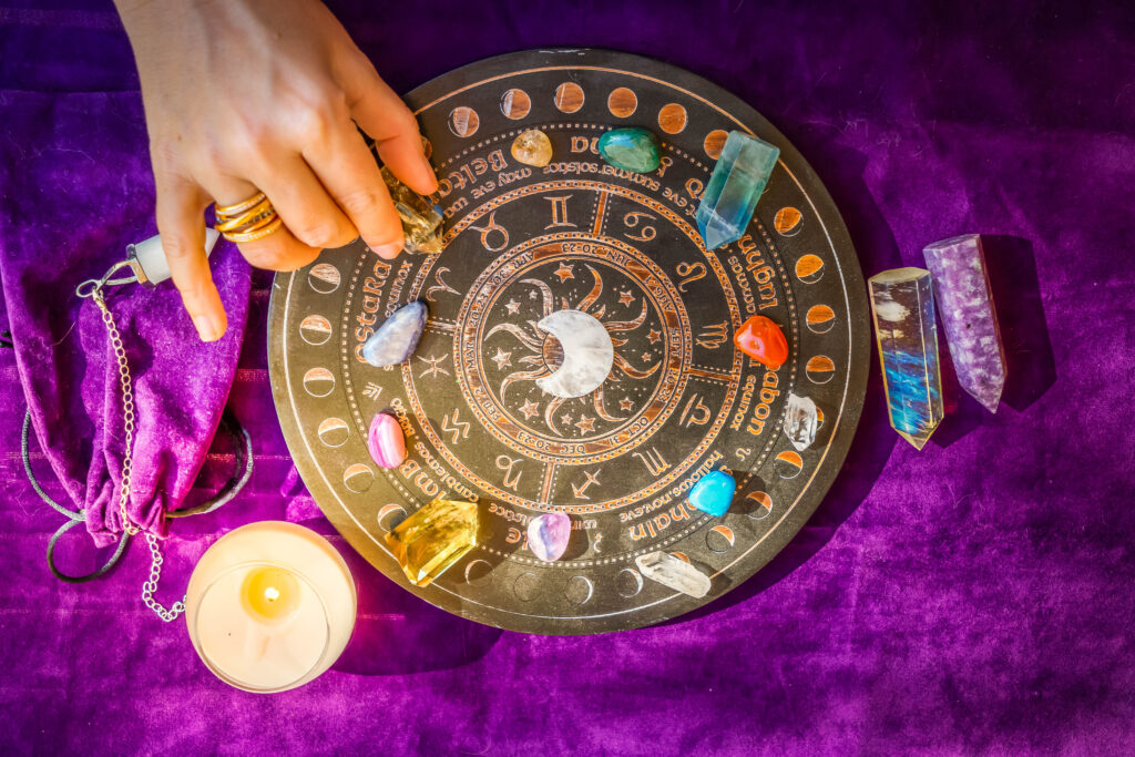 Astrologische Platte mit vielen Steinen darauf und eine Hand die einen Stein bewegt