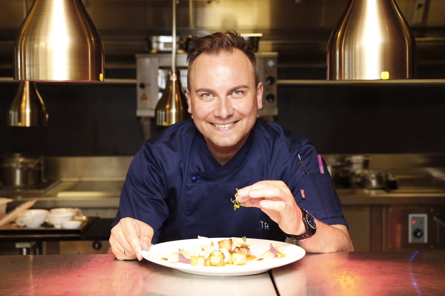 Tim Raue sitzt und isst etwas