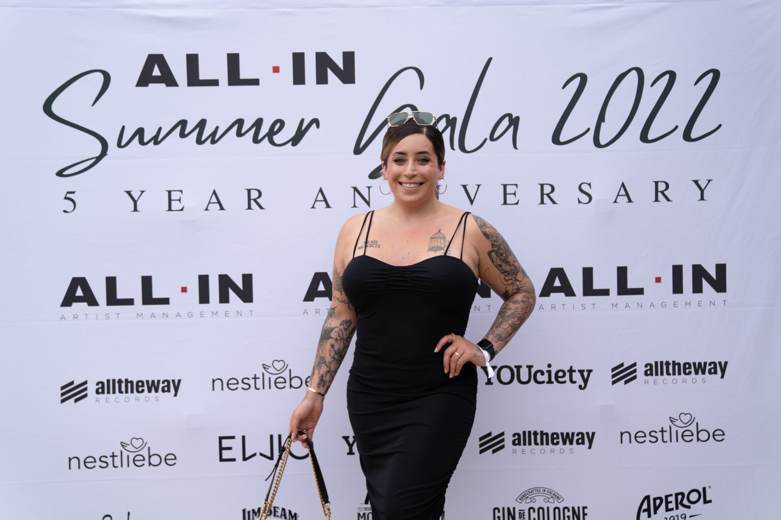 Jolina Mennen steht vor einem Plakat in schwarzem Kleid